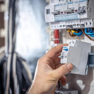 male-electrician-works-switchboard-with-electrical-connecting-cable